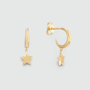 A pair of gold-toned dangle earrings on a light gray background. One earring is shown front-facing with a five-pointed star, and the other is shown from the side/back, displaying a crescent moon shape with a small hanging star.